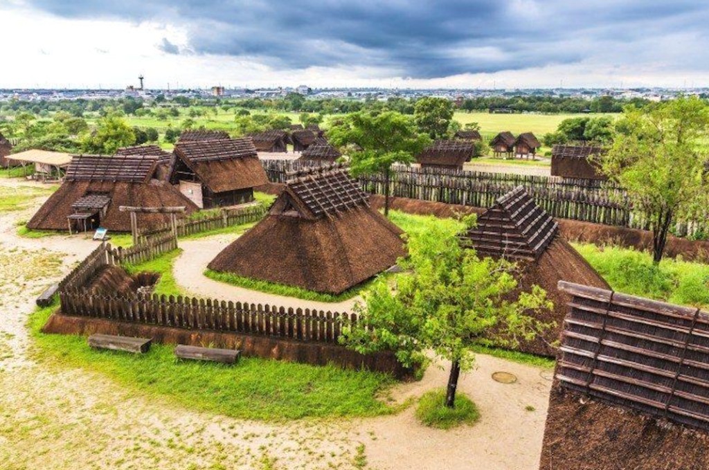 Reconstrução de aldeia fortificada do período Yayoi com habitações de telhado de palha e paliçadas — o período Yayoi introduziu agricultura e novas formas de organização social no Japão
